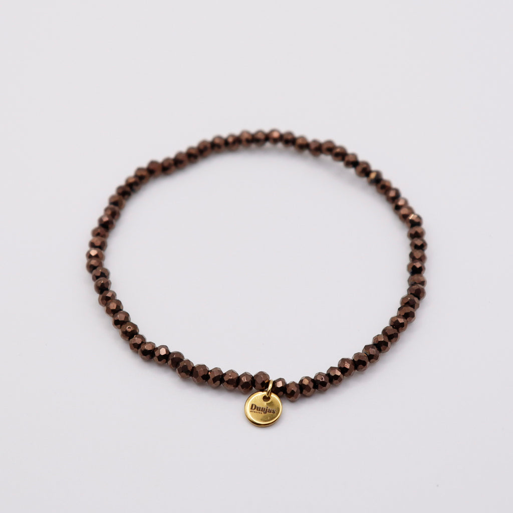 Elastisches Armband mit dunkelbraunen Glasperlen und goldenem Dunjas Atelier Charm, handgemacht in Zürich