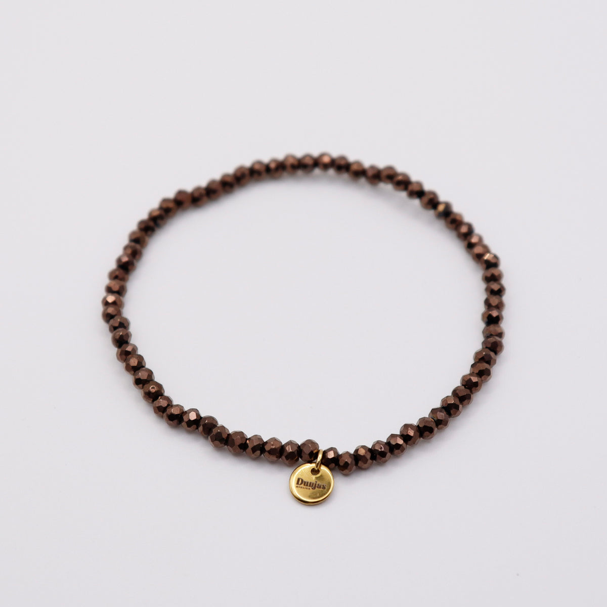 Elastisches Armband mit dunkelbraunen Glasperlen und goldenem Dunjas Atelier Charm, handgemacht in Zürich