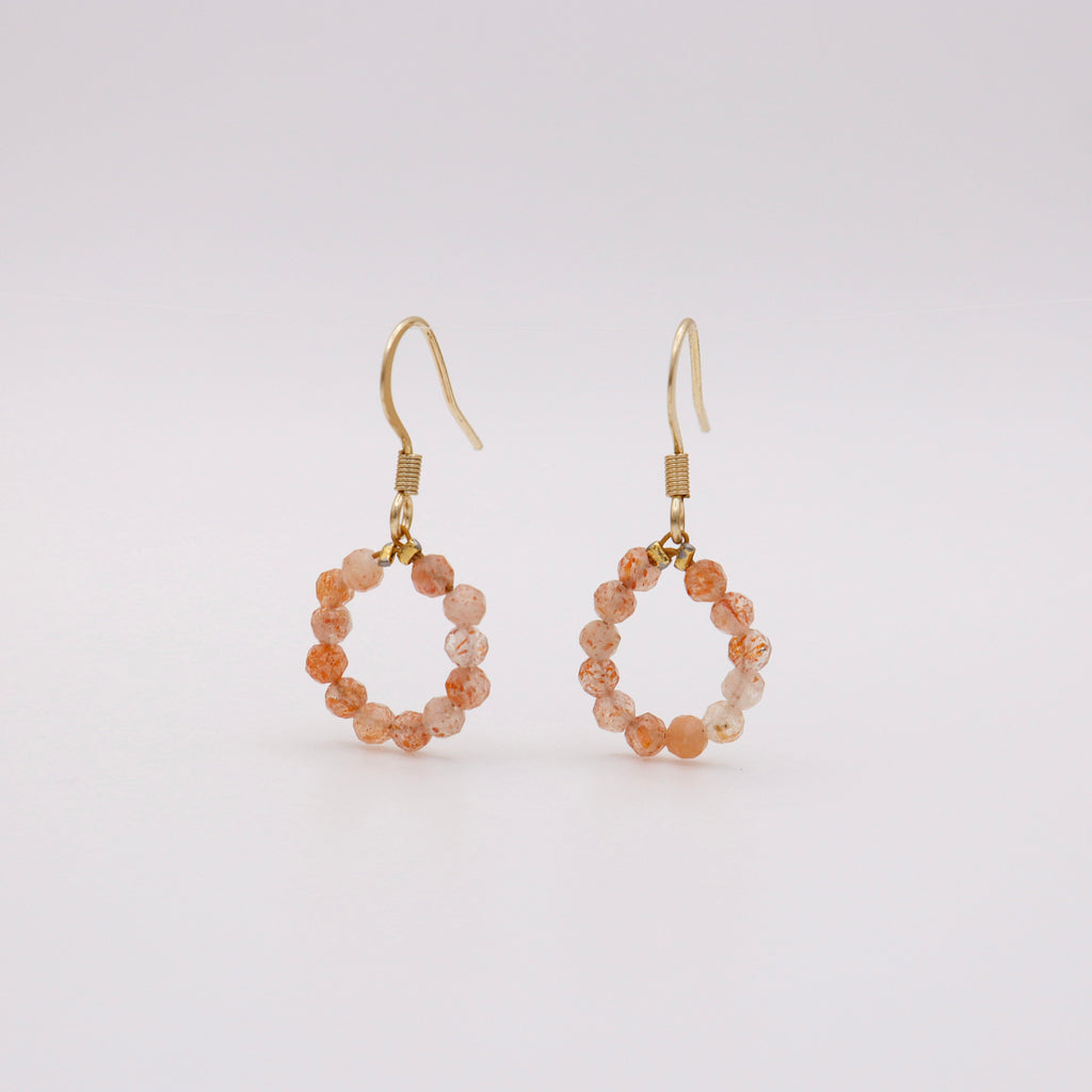 Ohrhaken mit Sonnenstein – pfirsich-orangefarbener Steinperlen-Kreis auf goldenem Edelstahlhaken, handgemacht in Dunjas Atelier Zürich
