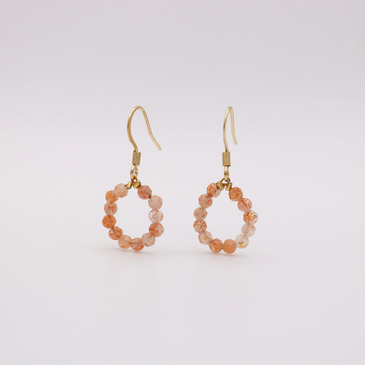 Ohrhaken mit Sonnenstein – pfirsich-orangefarbener Steinperlen-Kreis auf goldenem Edelstahlhaken, handgemacht in Dunjas Atelier Zürich
